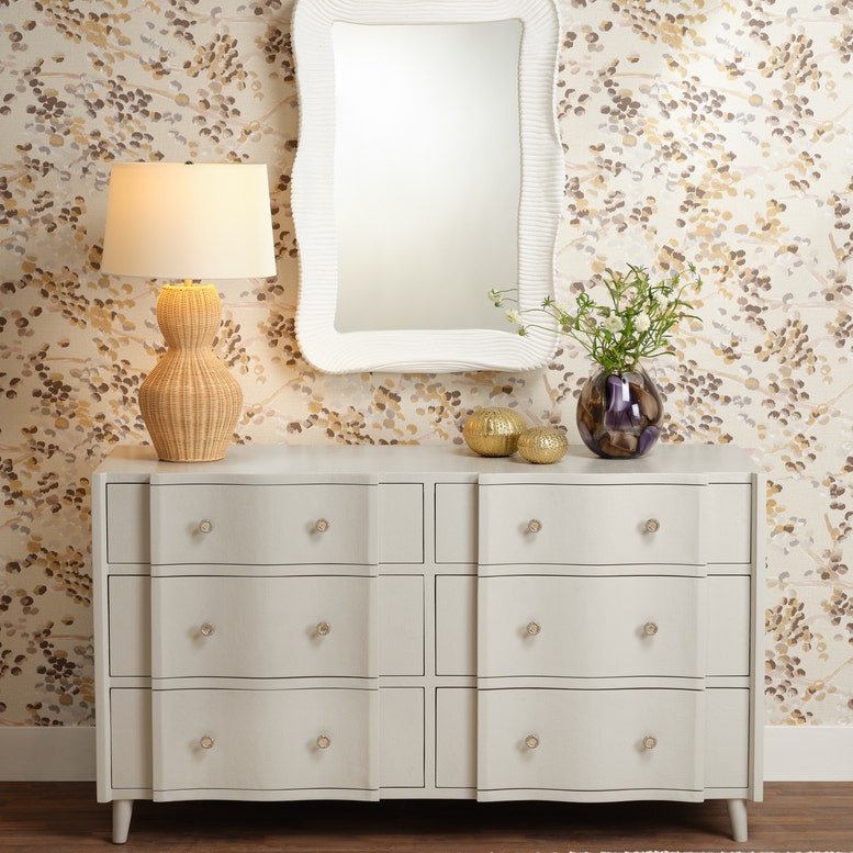 White dresser with decorative items against a patterned wall