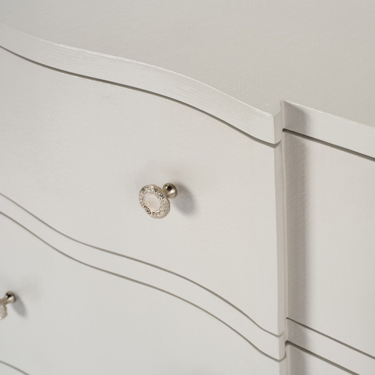 Close-up of a white dresser with a decorative silver handle.