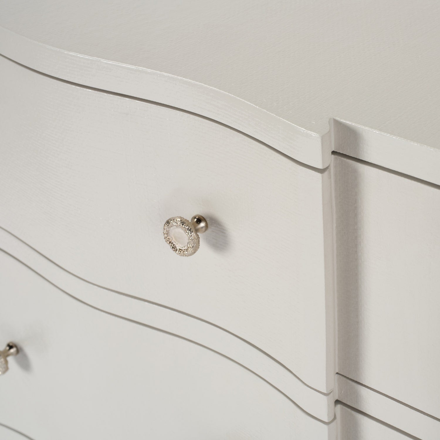 Close-up of a white dresser with a decorative silver handle.