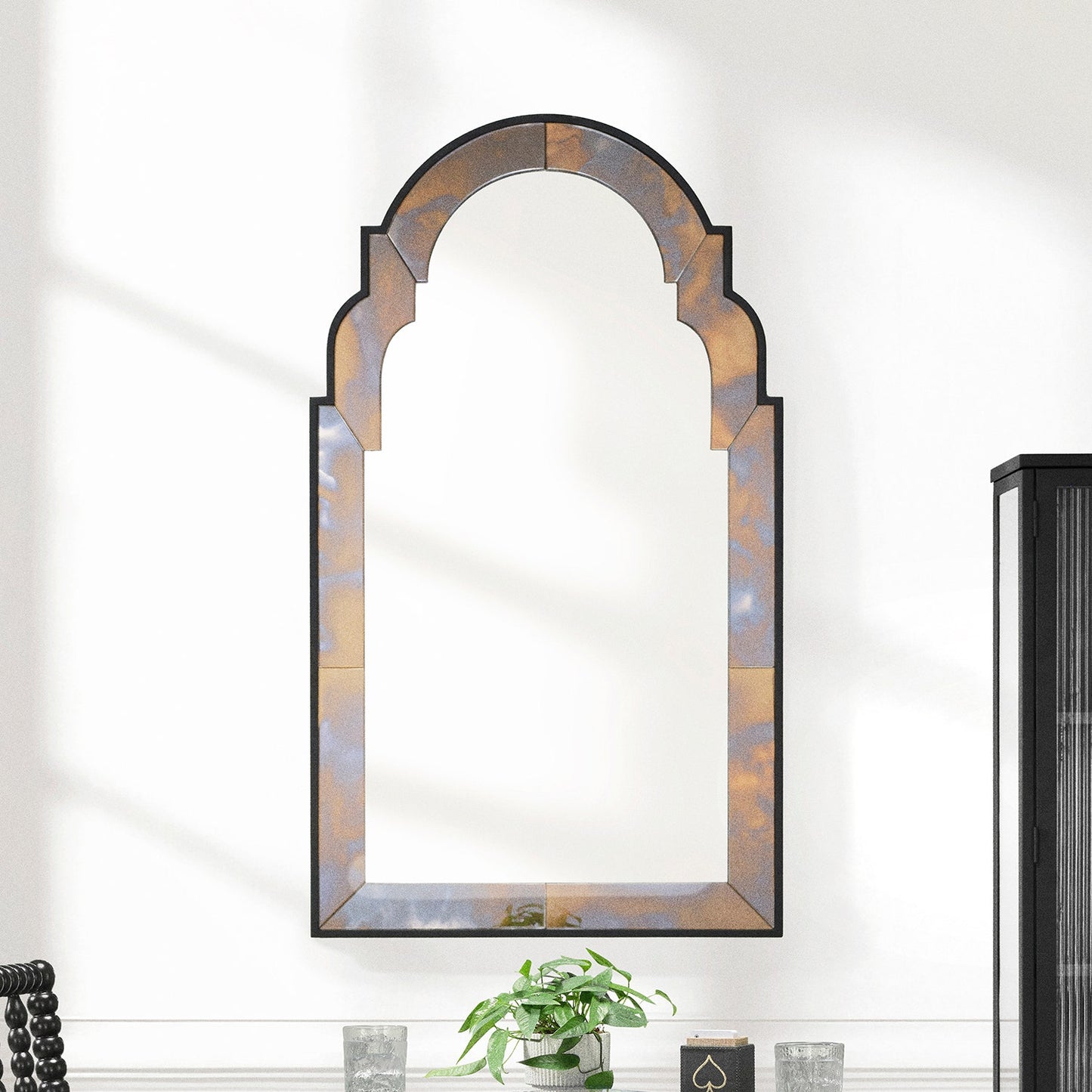 Decorative wall mirror with a decorative frame on a white wall.