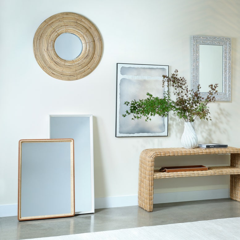 Living room with various mirrors and a vase on a table.