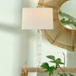 Table lamp with a decorative mirror and plant on a light green wall background