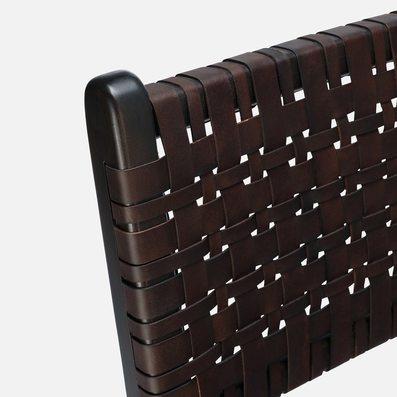 Close-up of a brown woven chair backrest with a black armrest on a white background