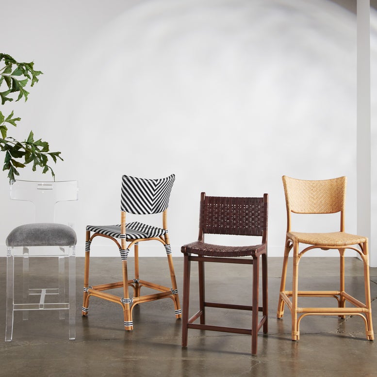 Four different styles of bar stools against a white wall.