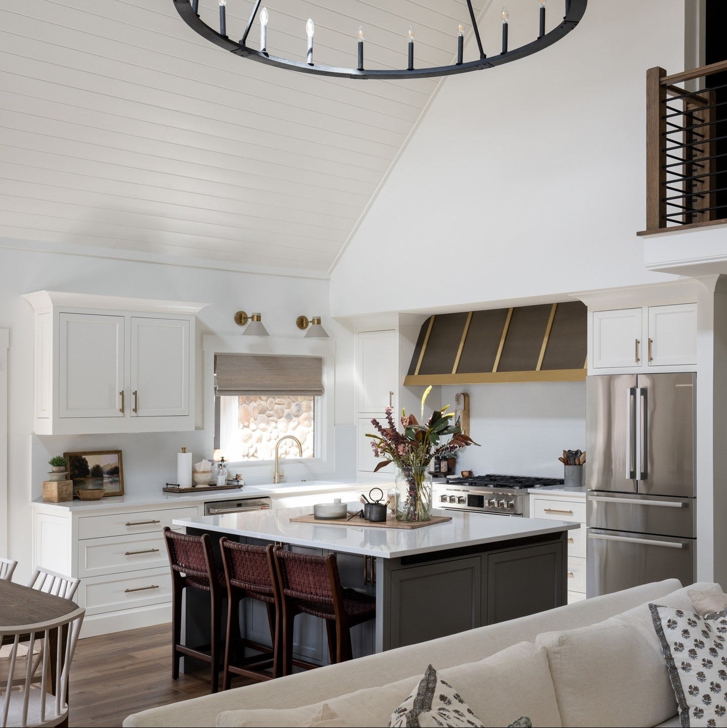 Modern kitchen with a large chandelier, island, and stainless steel appliances.