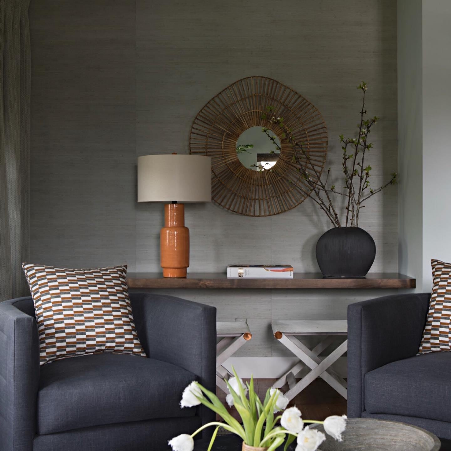 Modern living room with dark gray chairs, a wooden console table, and decorative items.