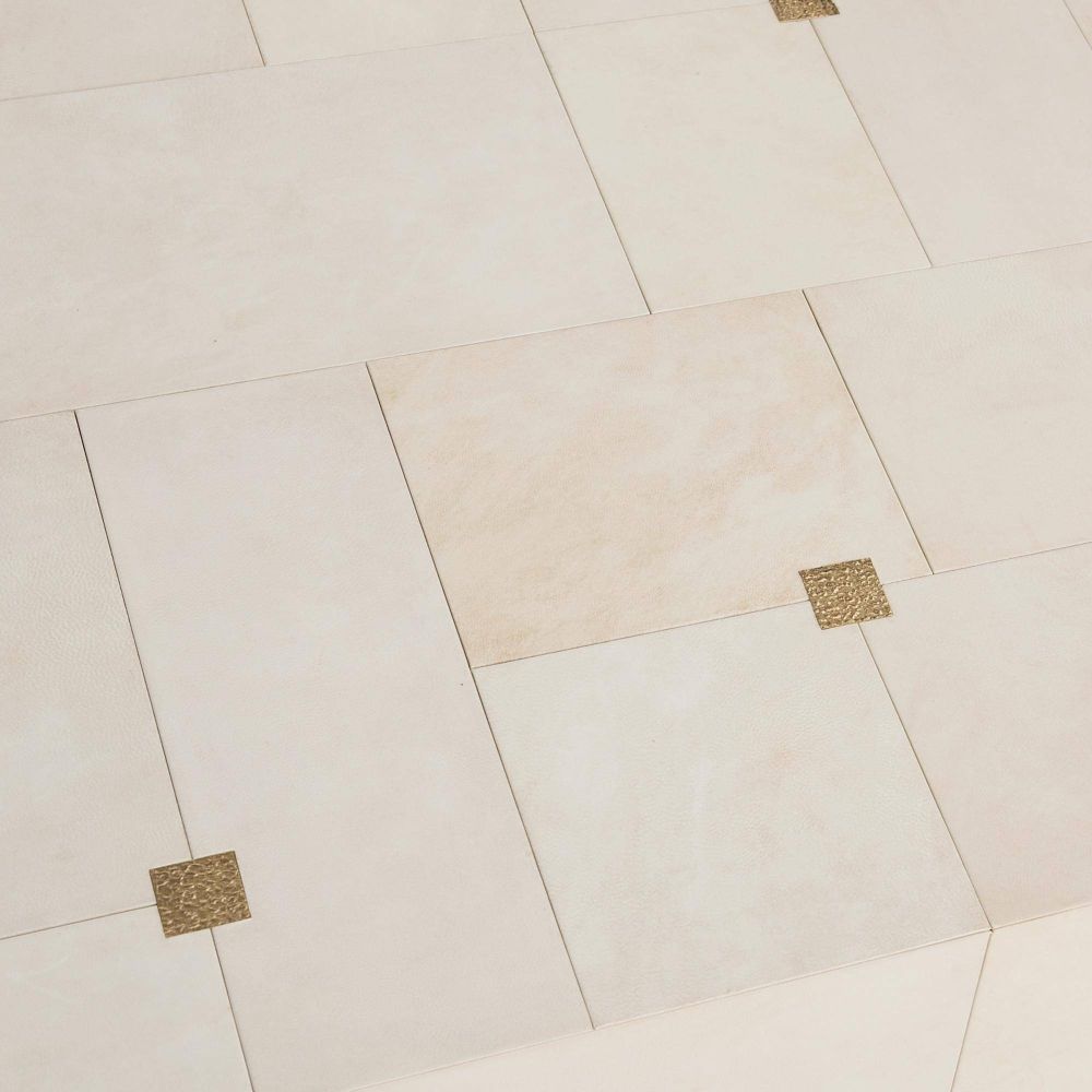 Beige tiles with gold accents arranged in a herringbone pattern on a light background