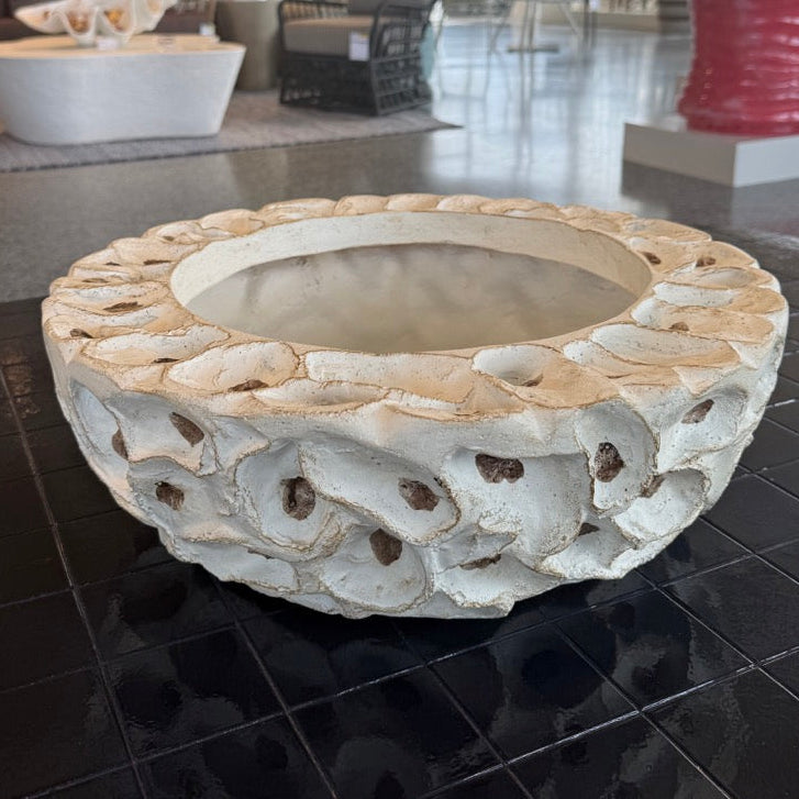 Decorative stone bowl on a black tiled floor with a modern interior setting in the background.