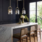Modern kitchen island with marble countertop, pendant lights, and chairs.