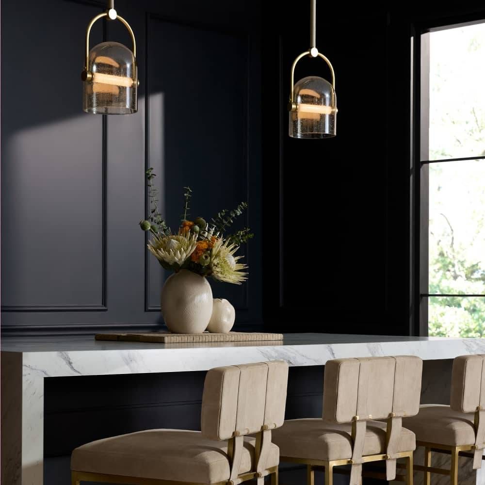 Modern dining room with marble table, beige chairs, and pendant lights.