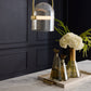 Decorative pendant light fixture with floral arrangement on a marble surface against a dark paneled wall.