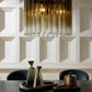 Modern chandelier hanging above a table with decorative items against a paneled wall.