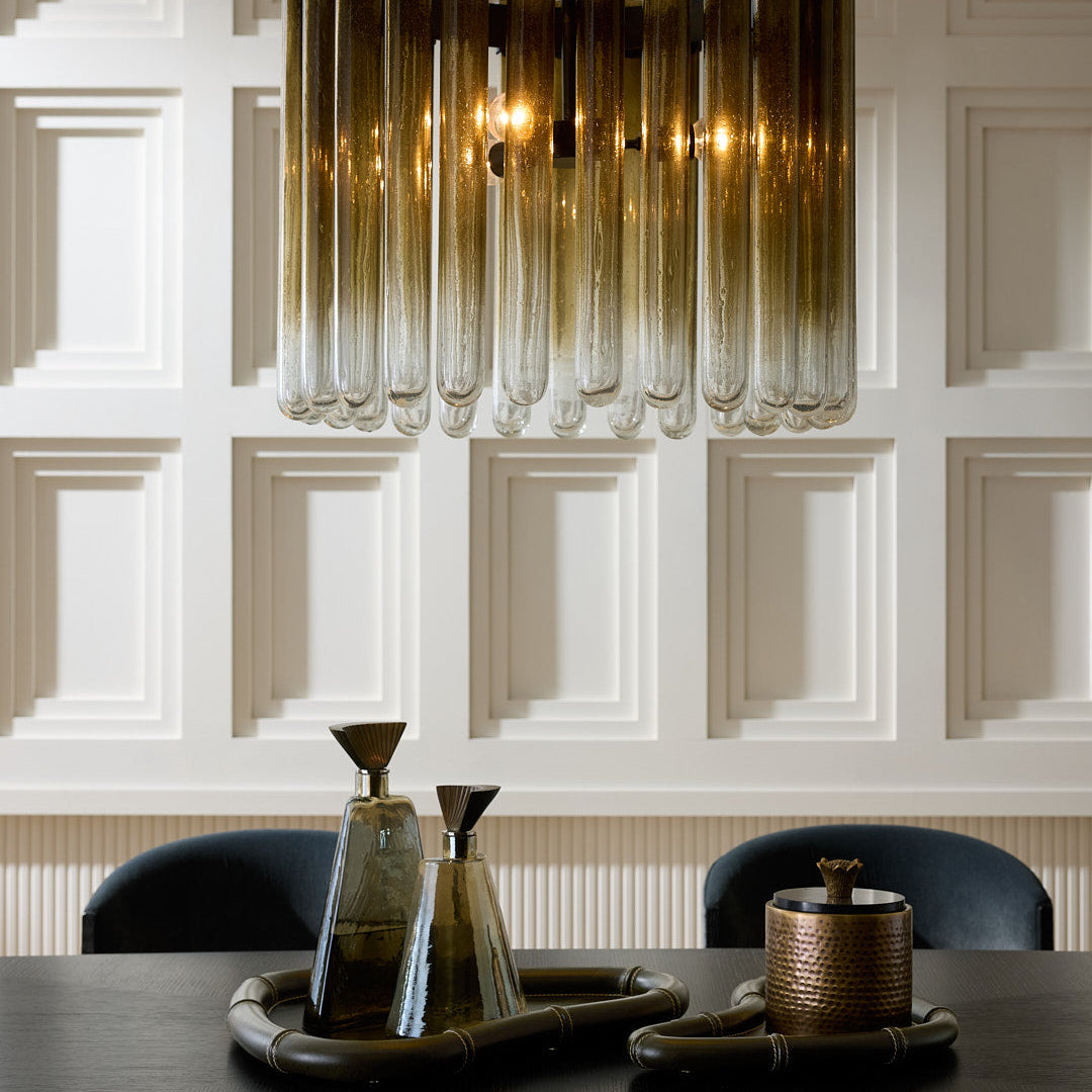 Modern chandelier hanging above a table with decorative items against a paneled wall.