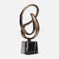 Bronze abstract sculpture on a black marble base against a white background