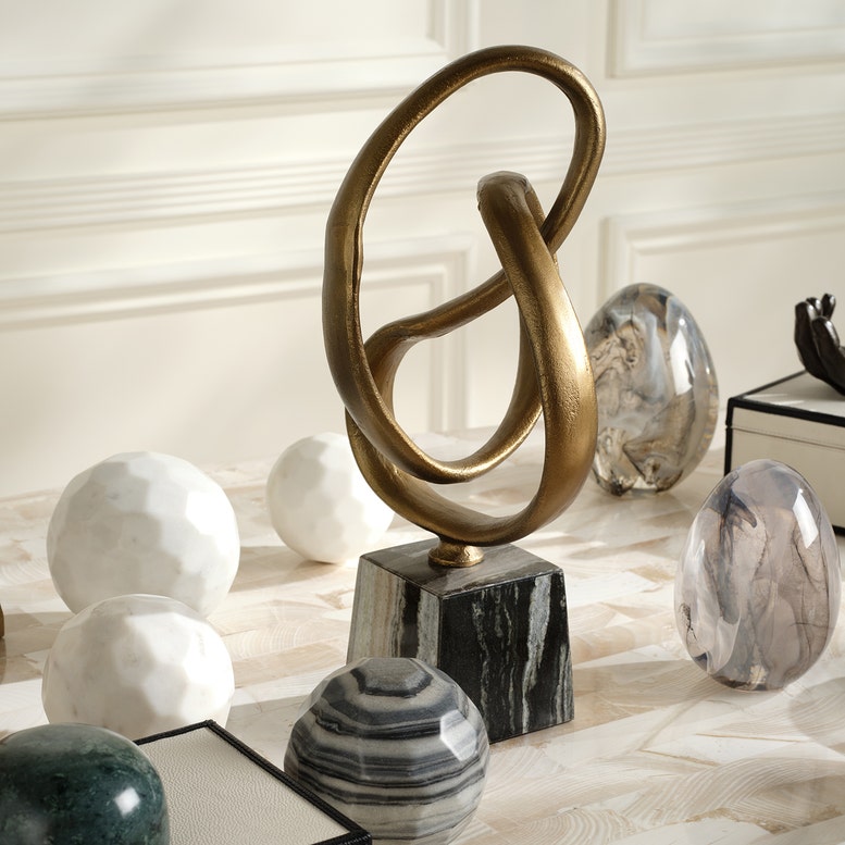 Decorative sculpture on a marble base with spherical marble ornaments in a room setting.
