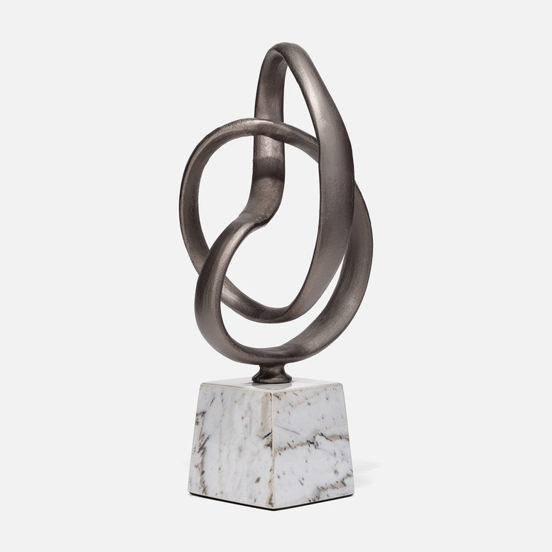 Abstract metal sculpture on a marble base against a white background