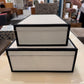 Two decorative boxes stacked on a surface with a blurred indoor background
