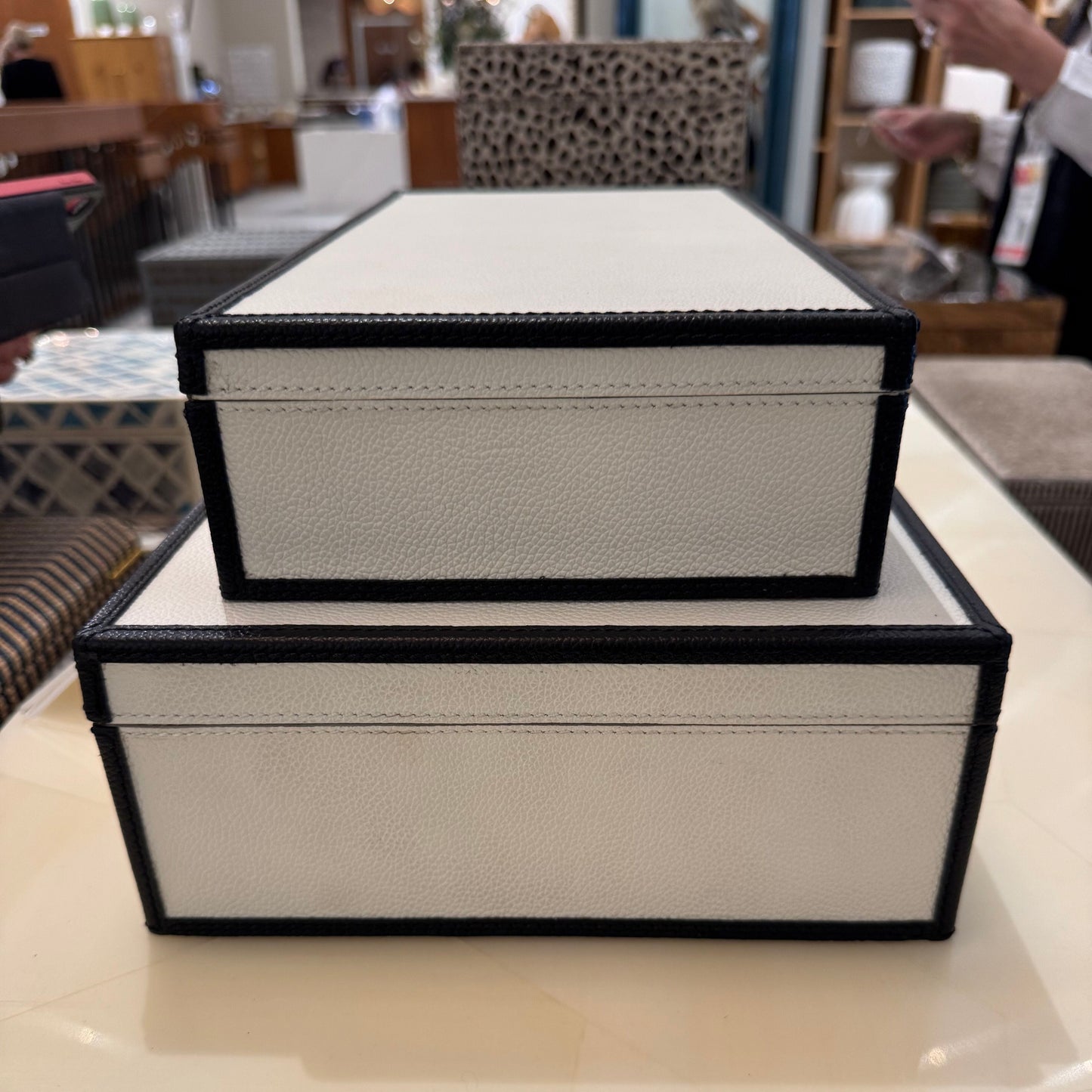 Two decorative boxes stacked on a surface with a blurred indoor background