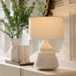 White ceramic lamp on a cabinet with decorative plants in the background