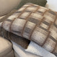 Plaid-patterned pillow on a sofa with a neutral background