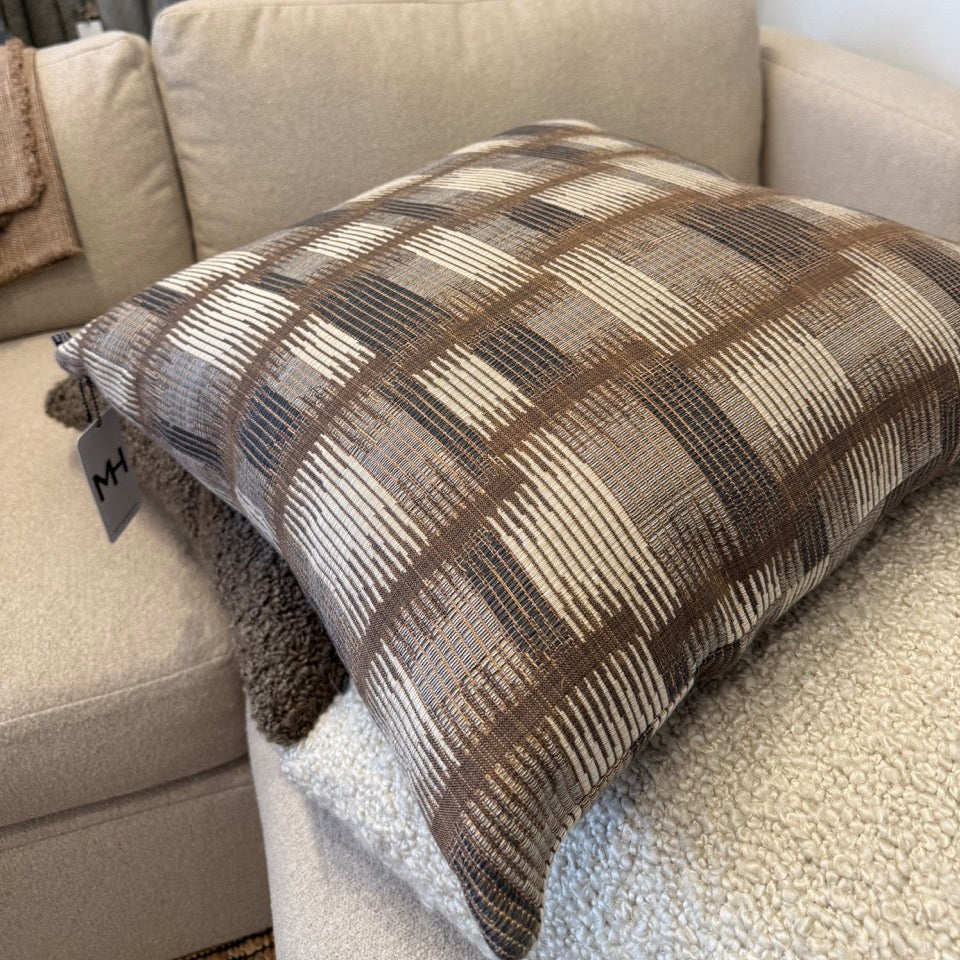 Plaid blanket draped over a beige sofa with a blurred background of more blankets.