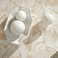 Marble-like textured surface with a white ceramic dish and spheres.