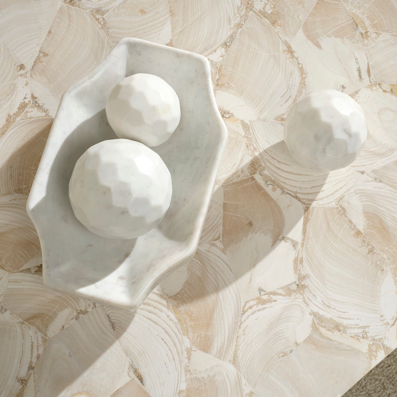 Marble-like textured surface with a white ceramic dish and spheres.