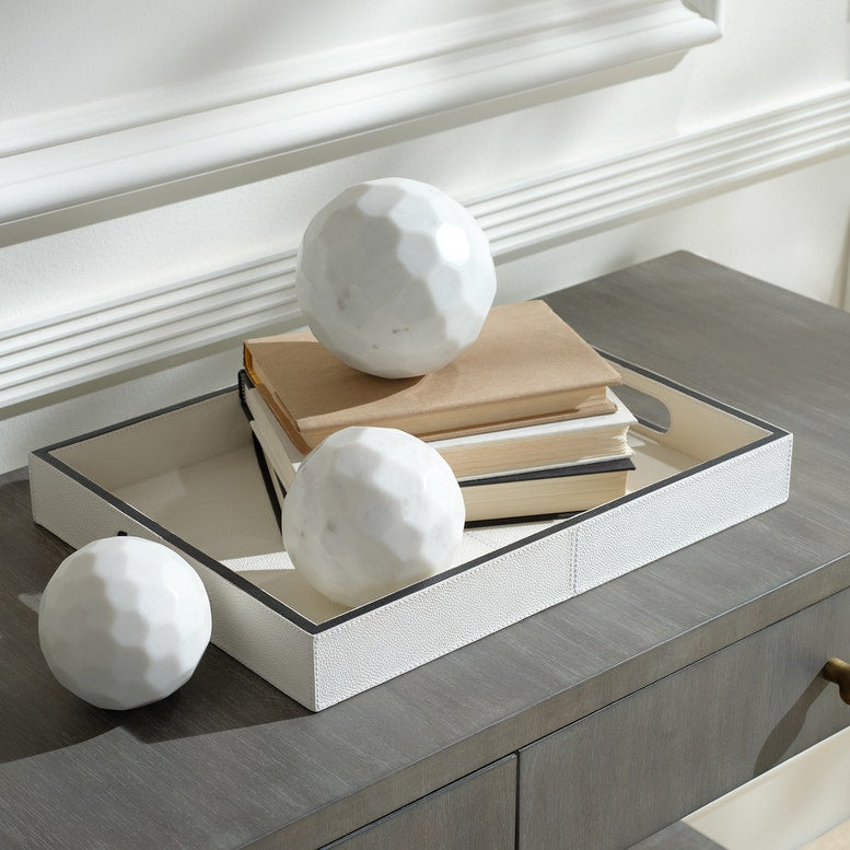 Decorative setup with books and marble spheres on a reflective surface