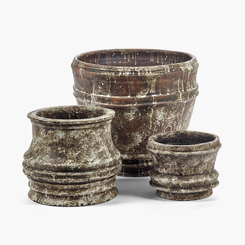 Three rustic brown stone planters of different sizes on a white background
