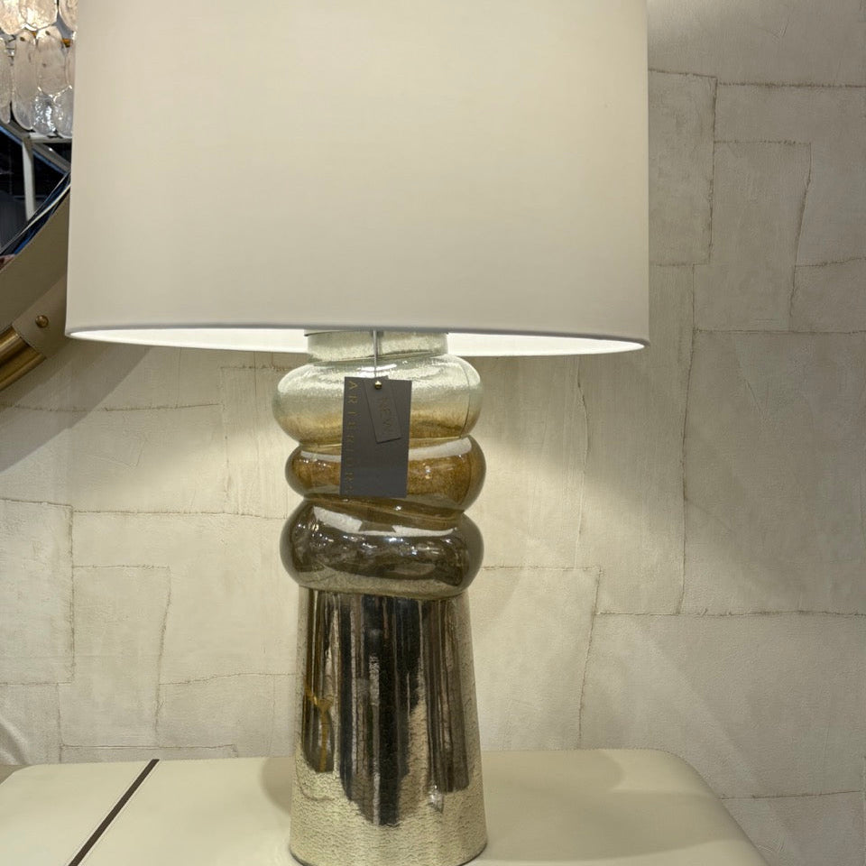 Table lamp with a white shade and metallic base on a display table.