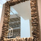 Decorative mirror with a textured brown frame on a wall.