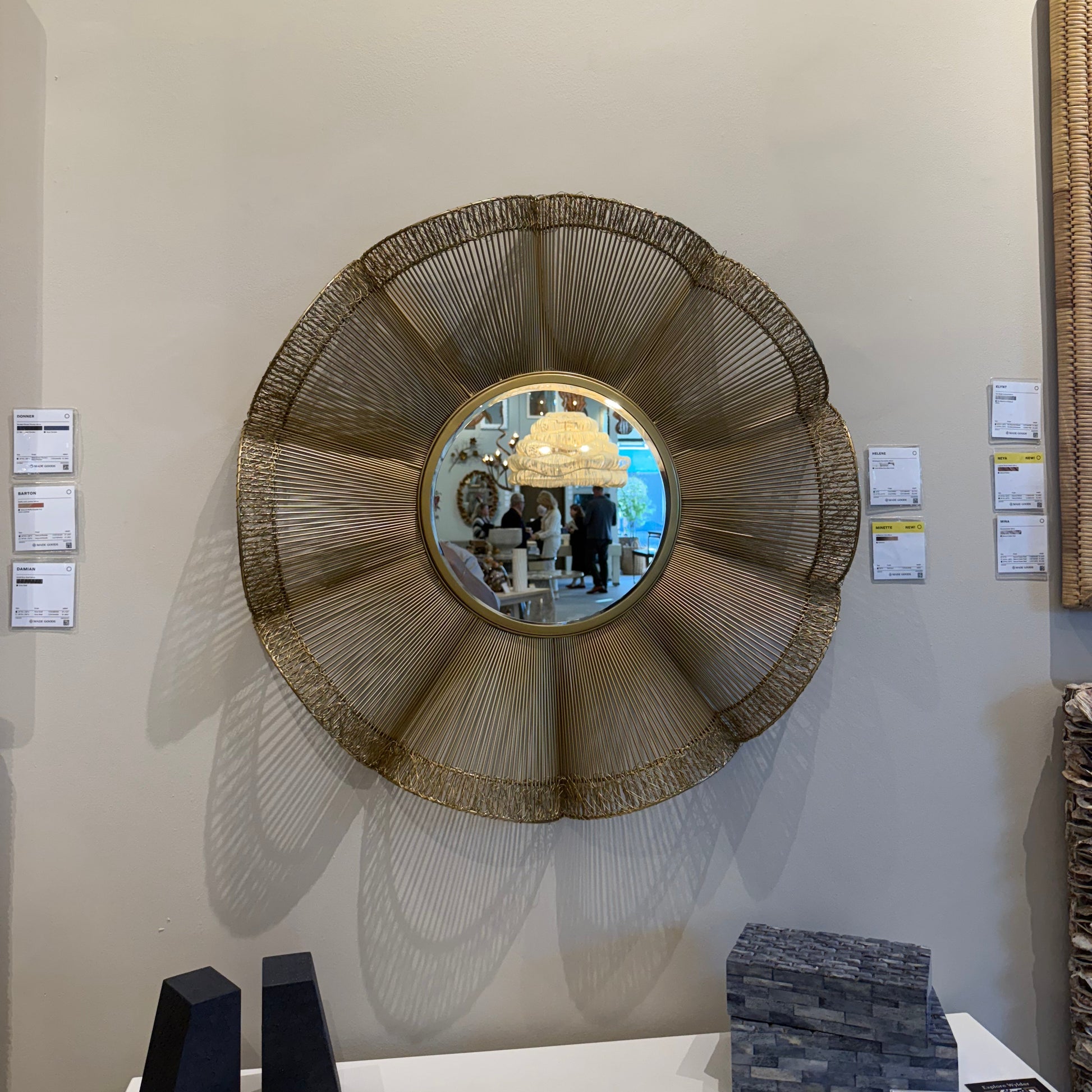 Round woven mirror on a wall with other decorative items