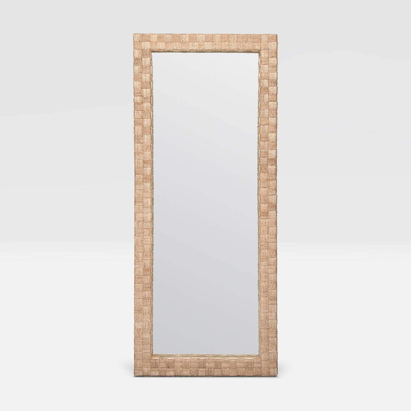 A tall, narrow rectangular floor mirror with a woven natural fiber frame in a light tan color, shown against a neutral light gray background.
