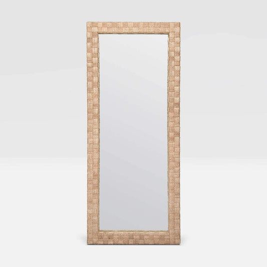 A tall, narrow rectangular floor mirror with a woven natural fiber frame in a light tan color, shown against a neutral light gray background.