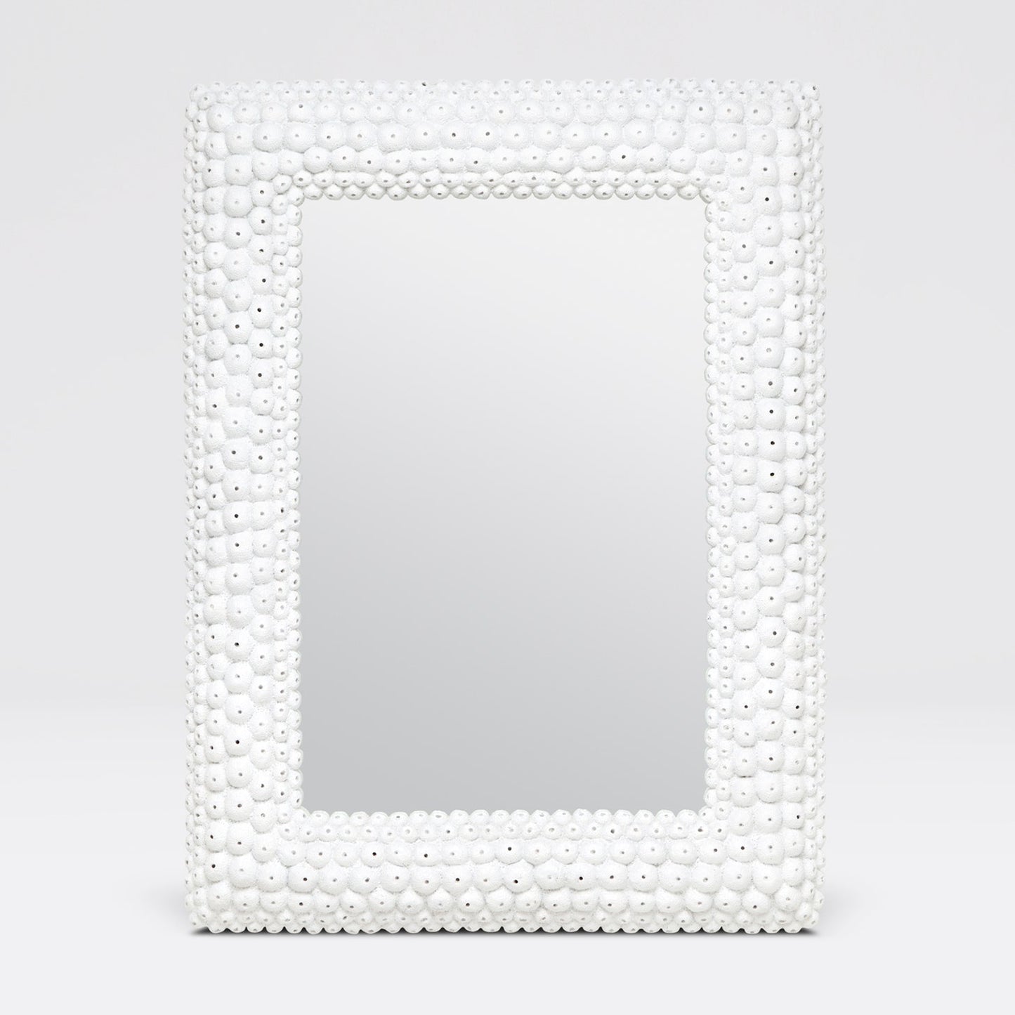 Mirror with a decorative white bead frame on a light gray background