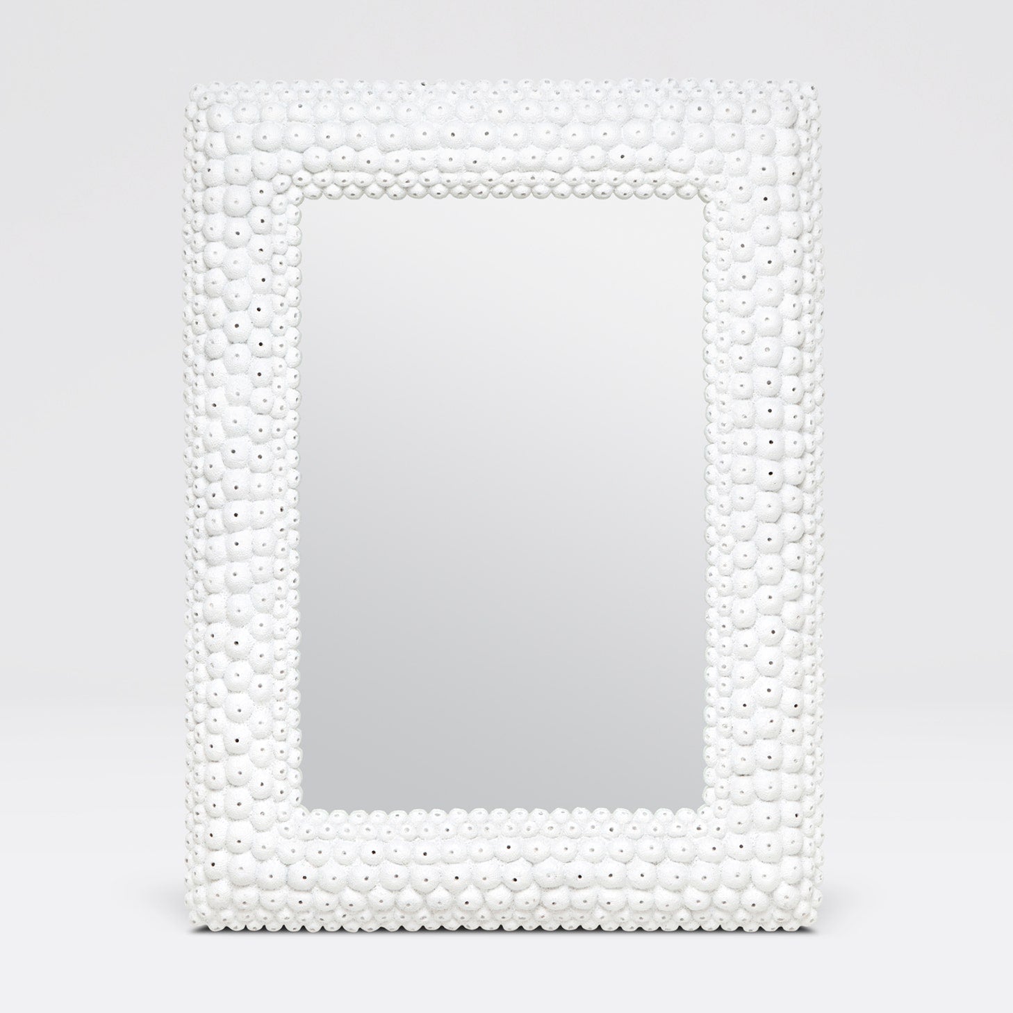 Mirror with a decorative white bead frame on a light gray background