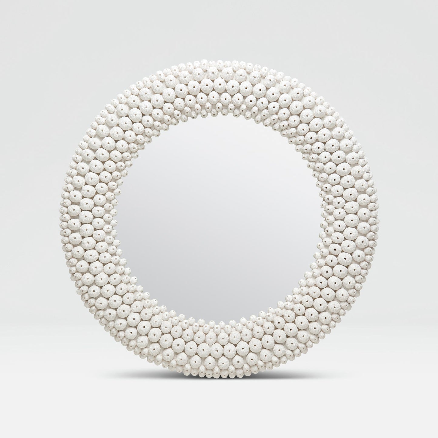 Round mirror with a white bead frame on a light gray background