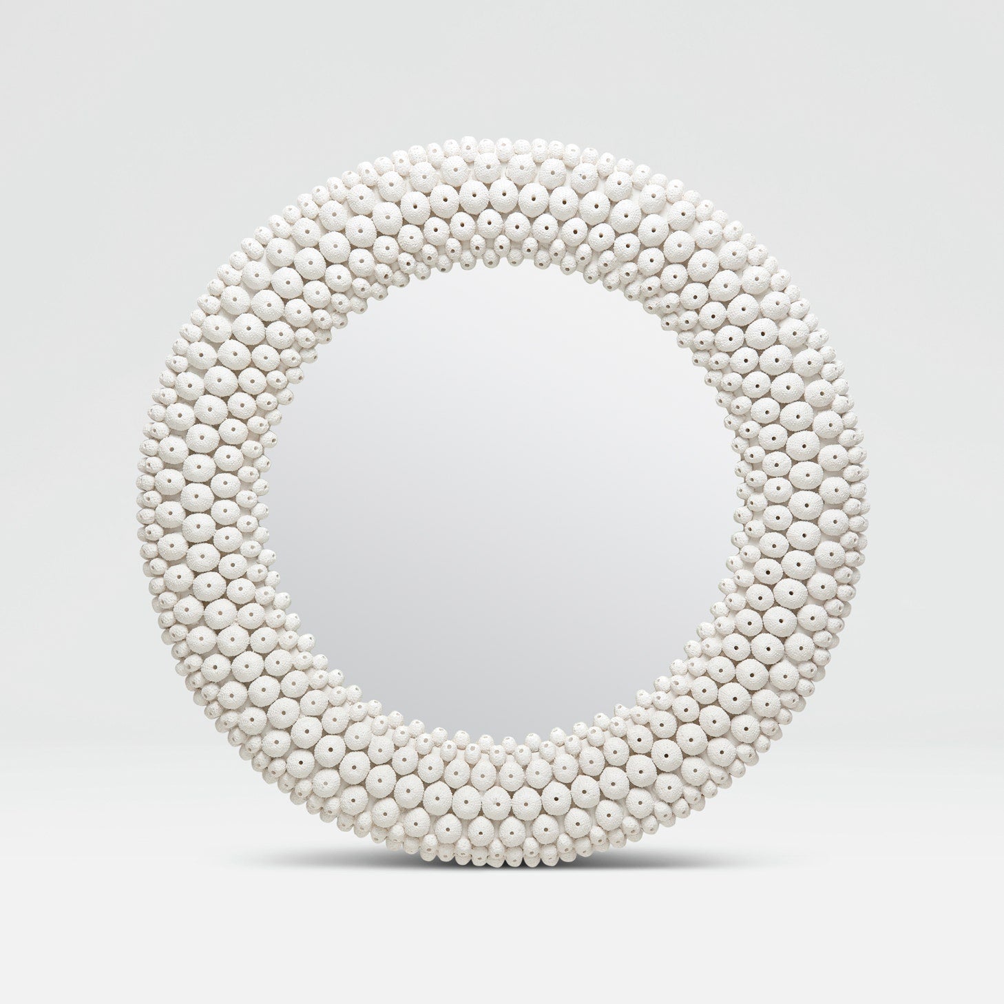 Round mirror with a white bead frame on a light gray background