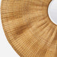 Close-up of a round woven natural straw or rattan rug with a circular cutout in the center, shown on a light neutral background.
