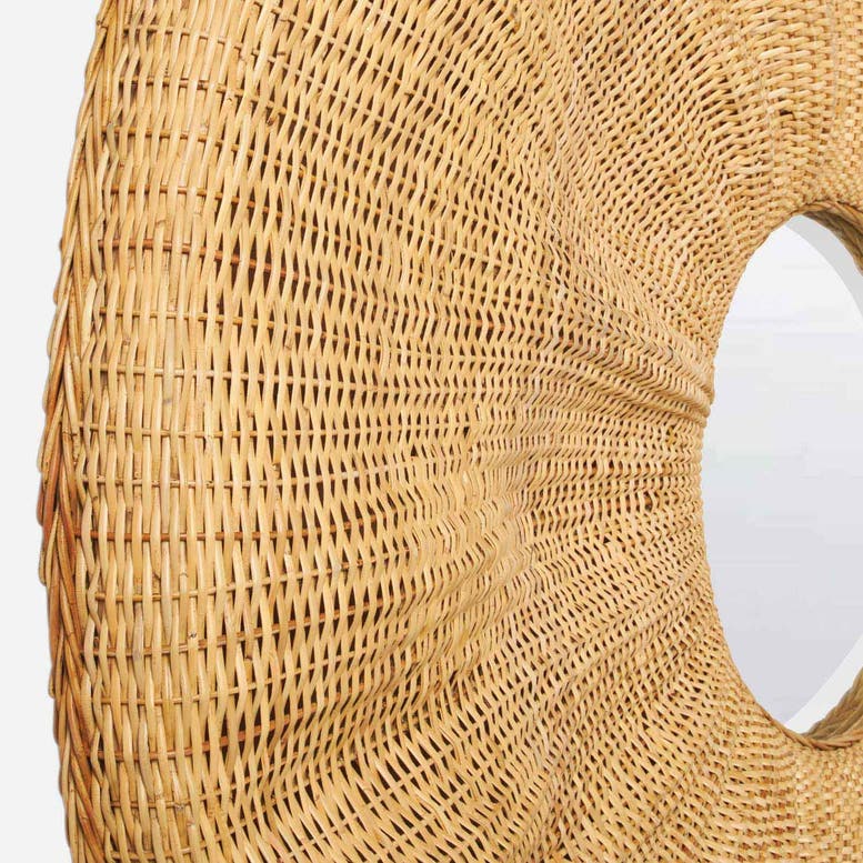 Close-up of a woven natural rattan or wicker circular wall mirror with a light wood frame, showing the detailed texture and weave pattern against a white background.