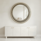 Round mirror with decorative frame above a white cabinet in a minimalistic room. torion