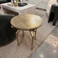 Round gold coffee table in a living room setting with furniture and decor.