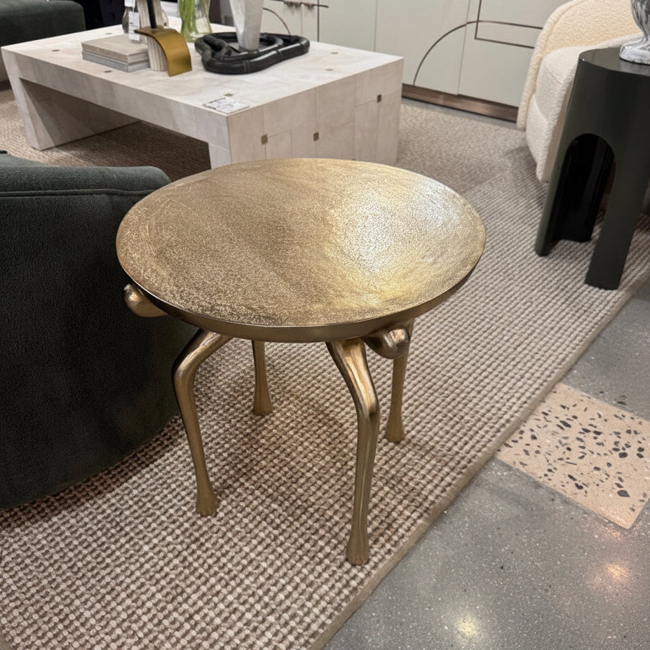 Round gold coffee table in a living room setting with furniture and decor.