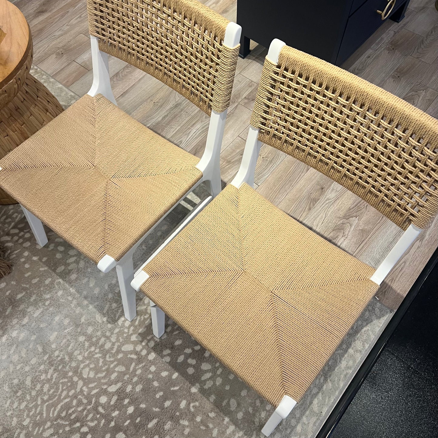Two wicker chairs with white frames on a patterned floor.