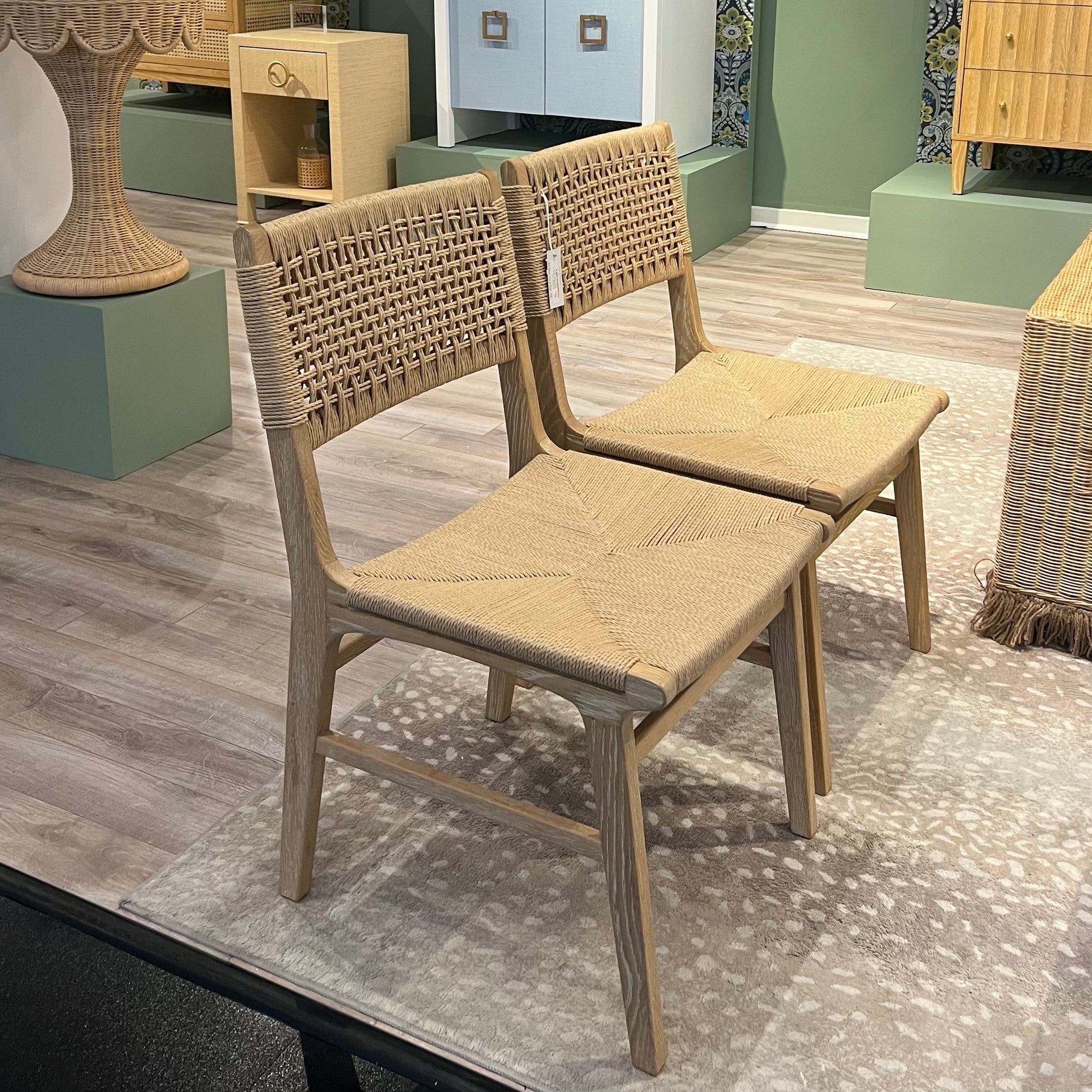 Pair of woven chairs on a patterned rug with a blurred indoor setting