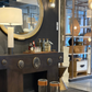 Decorative interior setting with a dark wooden console table, round mirror, and various decorative items.