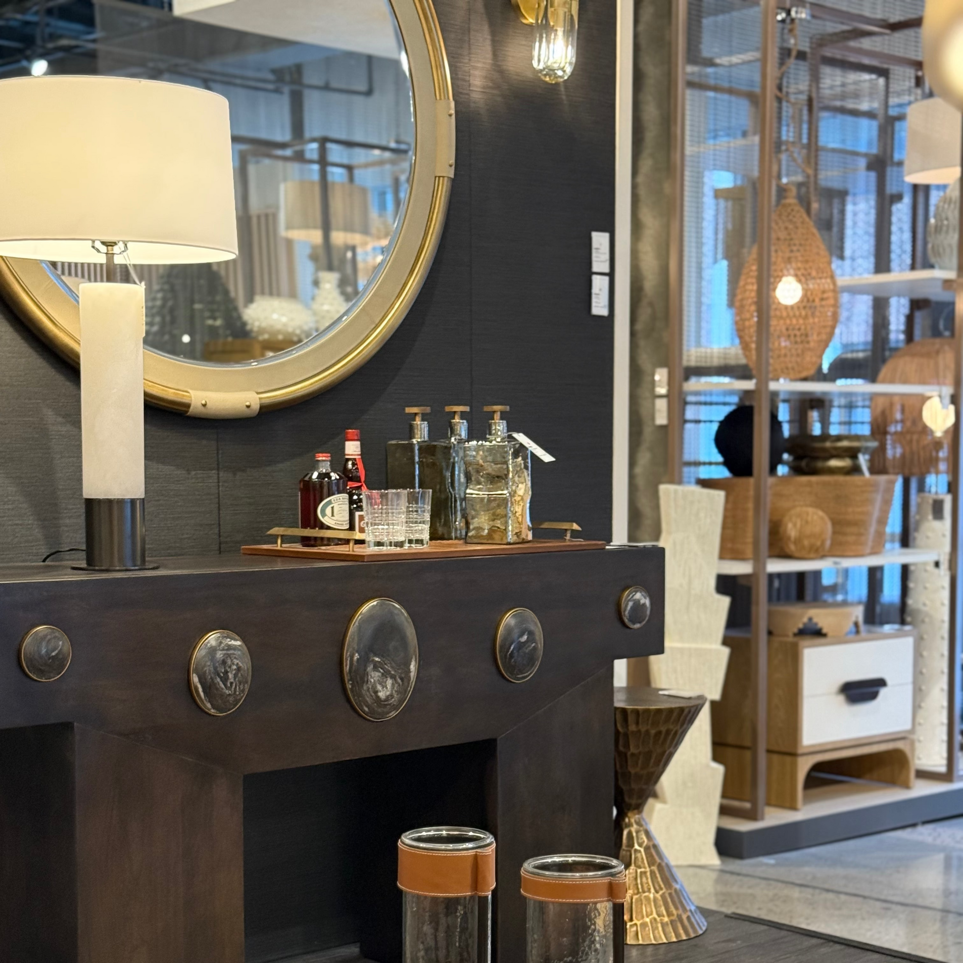 Decorative interior setting with a dark wooden console table, round mirror, and various decorative items.