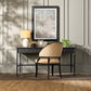 Decorative desk with chair, lamp, and framed artwork in a room with panelled walls.