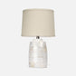 Table lamp with a decorative base and beige shade on a white background