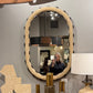 Round mirror with decorative items on a shelf in a room setting